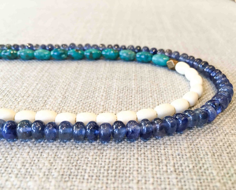 side view of gemstone bead necklace comprising turquoise, beige conch shell and blue sapphire