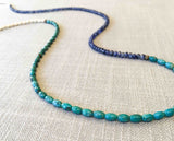 closeup of gemstone bead necklace comprising turquoise, beige conch shell and blue sapphire