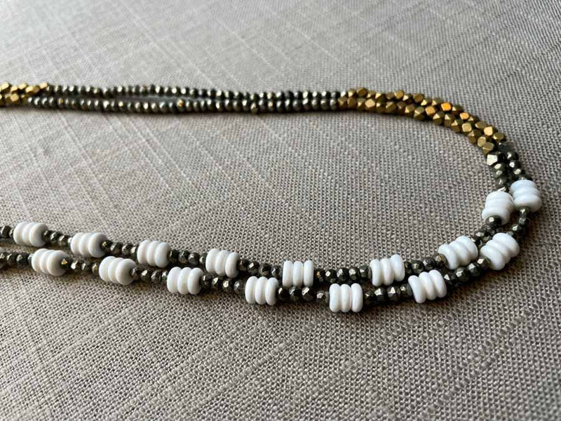 side view of gemstone bead necklace comprising white shell, bronze, dark grey pyrite