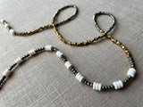 closeup of gemstone bead necklace comprising white shell, bronze, dark grey pyrite