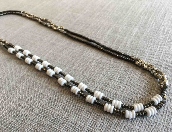 top view of gemstone bead necklace comprising white shell, silver and dark grey pyrite