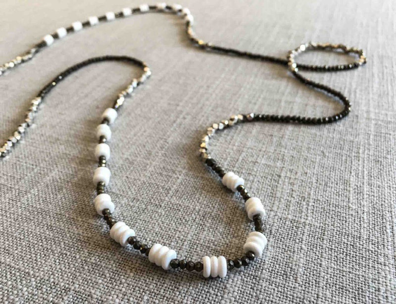 closeup of gemstone bead necklace comprising white shell, silver and dark grey pyrite