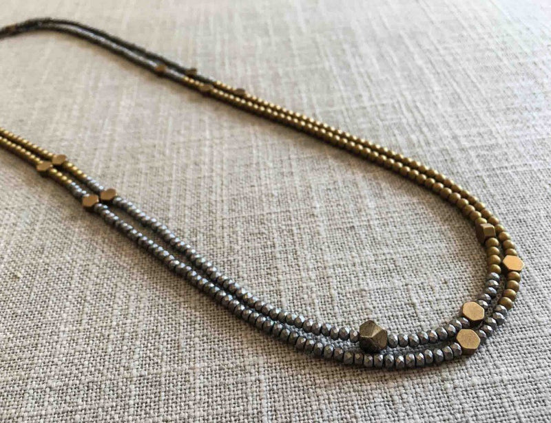 top view of gemstone bead necklace comprising gold hematite, matte silver hematite and bronze hex accents