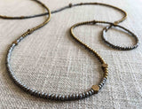 closeup of gemstone bead necklace comprising matte gold hematite, silver hematite and bronze hex accents