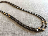 top view of gemstone bead necklace comprising smoky quartz, matte silver hematite and bronze hex accents