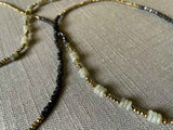 closeup of gemstone bead necklace comprising grey labradorite, dark bronze and golden pyrite