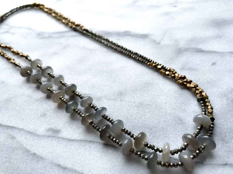 top view of gemstone bead necklace comprising grey moonstone, dark grey pyrite and bronze