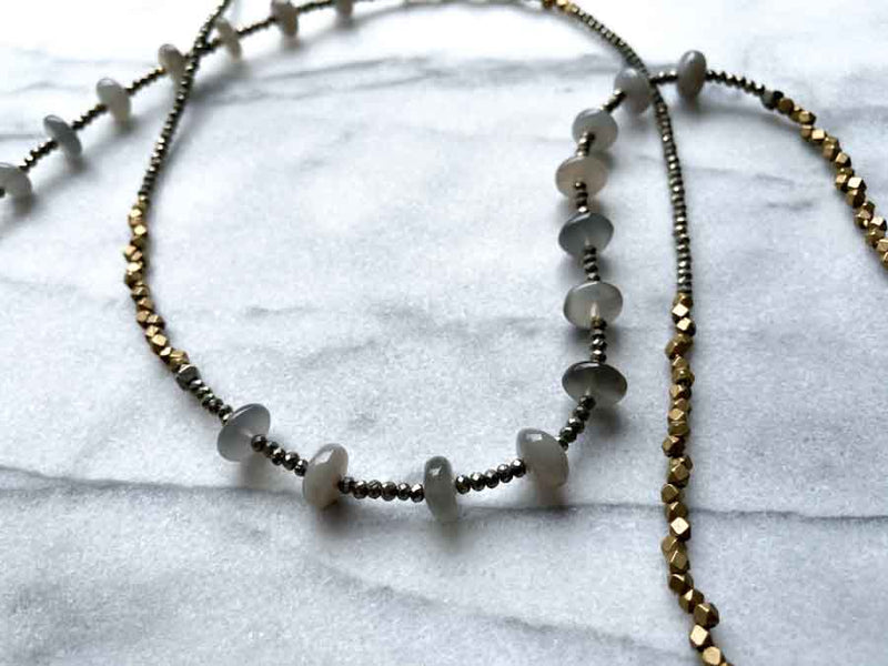 closeup of gemstone bead necklace comprising grey moonstone, dark grey pyrite and bronze