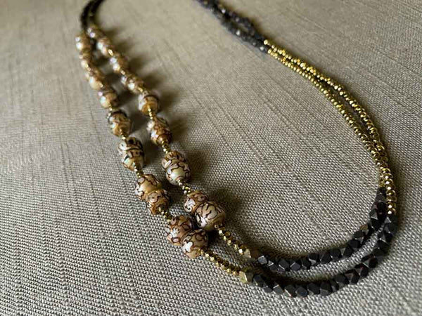 top view of gemstone bead necklace comprising neutral prayer beads, dark bronze and golden pyrite