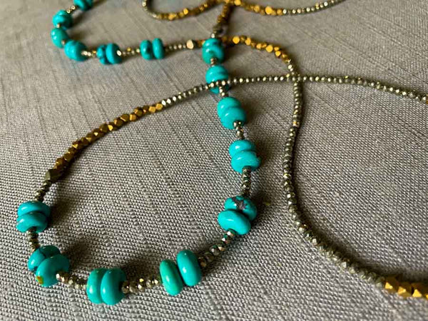 closeup of gemstone bead necklace comprising turquoise, bronze and dark grey pyrite