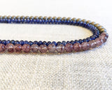 side view of gemstone bead necklace comprising light purple strawberry quartz, blue sapphire and bronze hematite