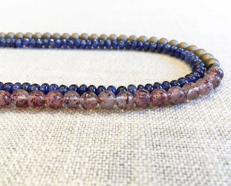 side view of gemstone bead necklace comprising light purple strawberry quartz, blue sapphire and bronze hematite