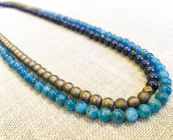 top view of gemstone bead necklace comprising dark blue lapis, aqua apatite and bronze hematite