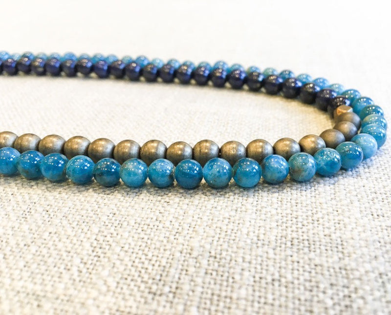 side view of gemstone bead necklace comprising dark blue lapis, aqua apatite and bronze hematite