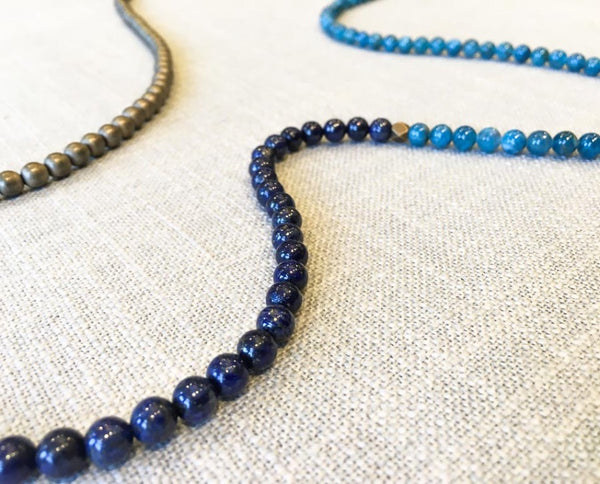 closeup of gemstone bead necklace comprising dark blue lapis, aqua apatite and bronze hematite