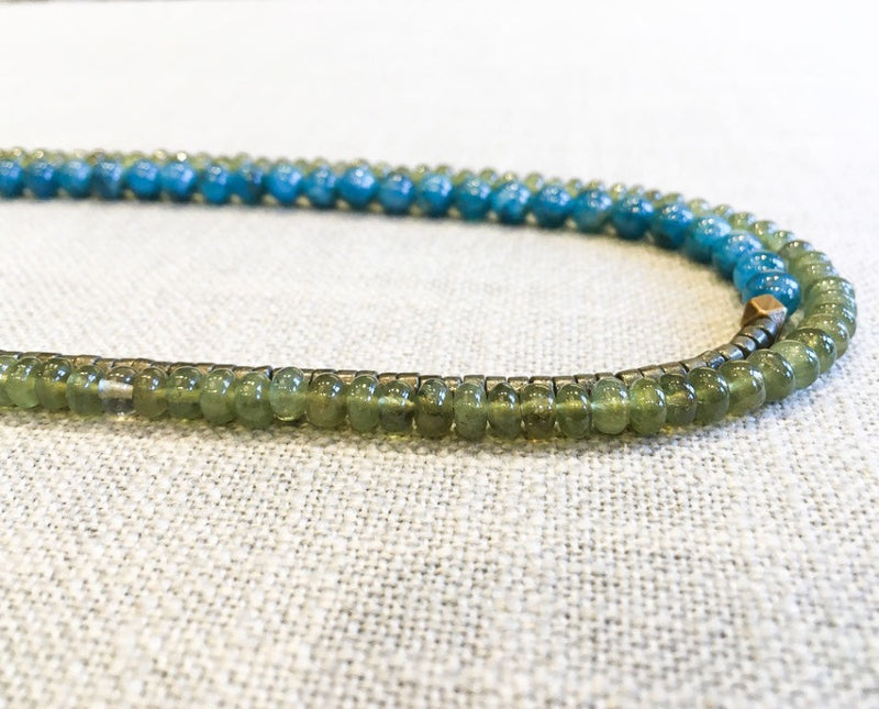 side view of gemstone bead necklace comprising green sapphire, aqua apatite and dark grey pyrite