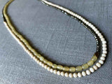 top view of gemstone bead necklace comprising blonde horn, white conch shell and dark grey pyrite