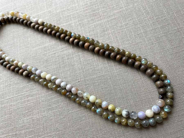 top view of gemstone bead necklace comprising neutral dendritic opal, green labradorite and exotic wood