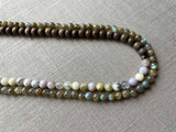 side view of gemstone bead necklace comprising neutral dendritic opal, green labradorite and exotic wood