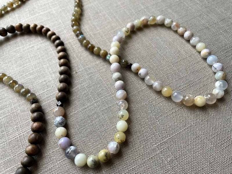 closeup of gemstone bead necklace comprising neutral dendritic opal, green labradorite and exotic wood