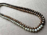 top view of gemstone bead necklace comprising off-white siberian moonstone, dark blush siberian moonstone and exotic wood