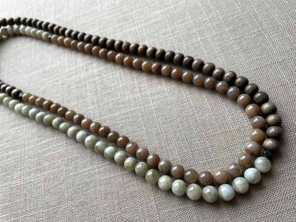 top view of gemstone bead necklace comprising off-white siberian moonstone, dark blush siberian moonstone and exotic wood