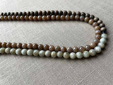 side view of gemstone bead necklace comprising off-white siberian moonstone, dark blush siberian moonstone and exotic wood