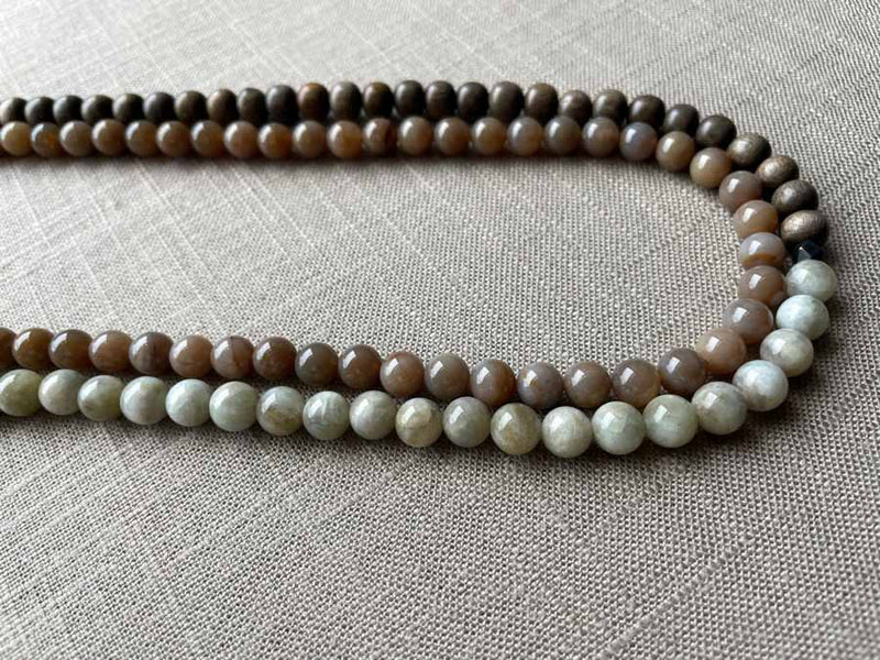 side view of gemstone bead necklace comprising off-white siberian moonstone, dark blush siberian moonstone and exotic wood