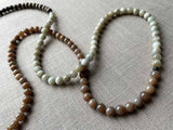 closeup of gemstone bead necklace comprising off-white siberian moonstone, dark blush siberian moonstone and exotic wood