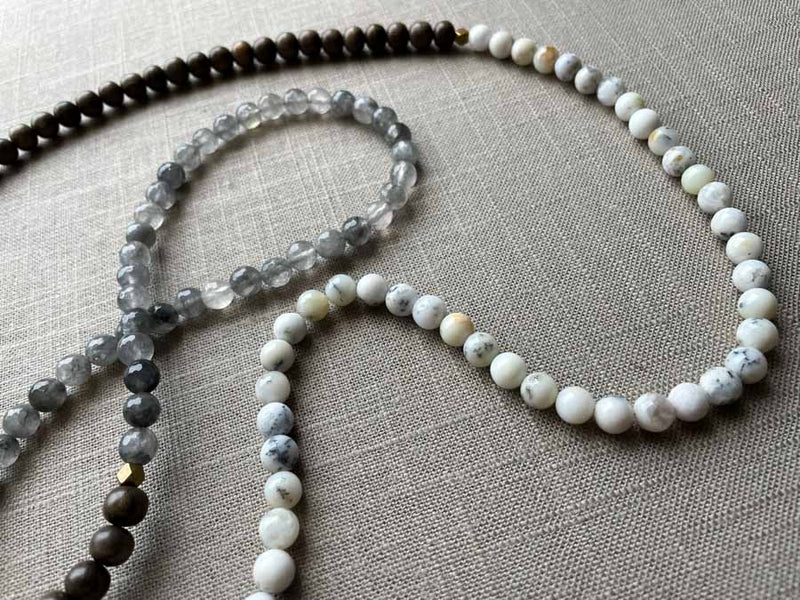 closeup of gemstone bead necklace comprising white speckled agate, black and white tourmalated quartz and exotic wood