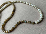 closeup of gemstone bead necklace comprising off-white siberian moonstone, green labradorite and exotic wood