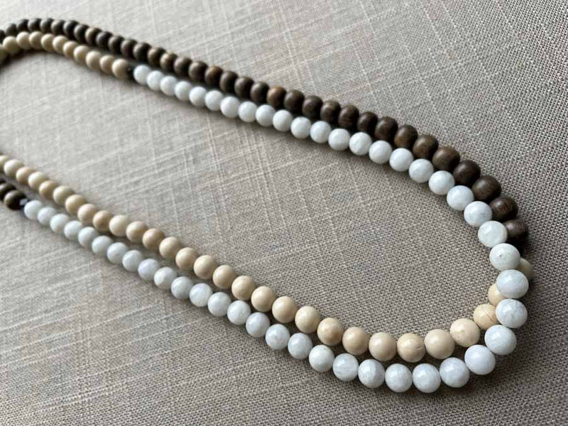 top view of gemstone bead necklace comprising white moonstone, off-white fossil jasper and exotic wood