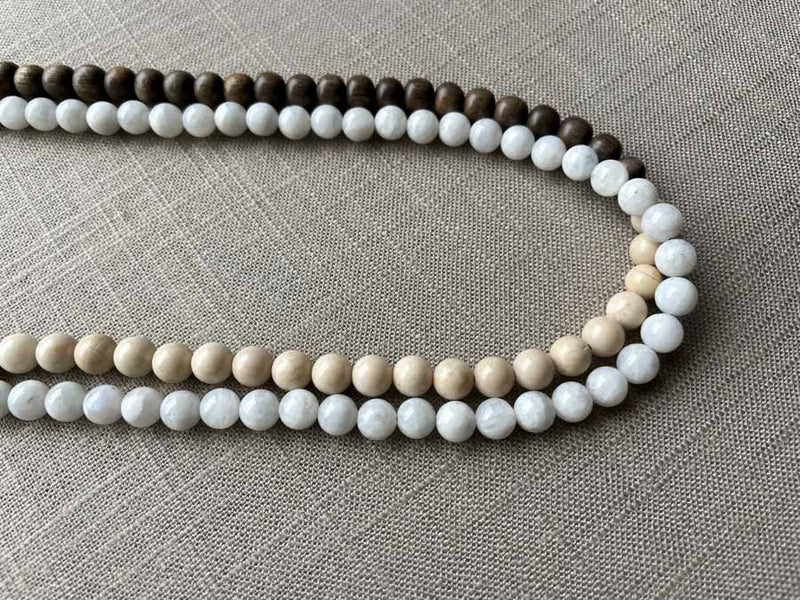 side view of gemstone bead necklace comprising white moonstone, off-white fossil jasper and exotic wood