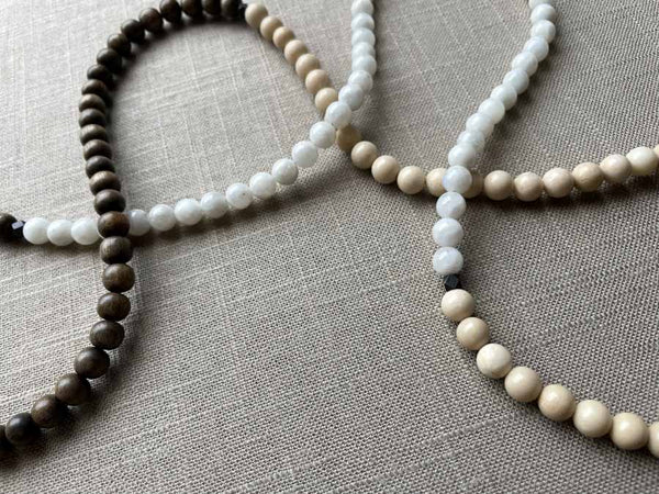 closeup of gemstone bead necklace comprising white moonstone, off-white fossil jasper and exotic wood