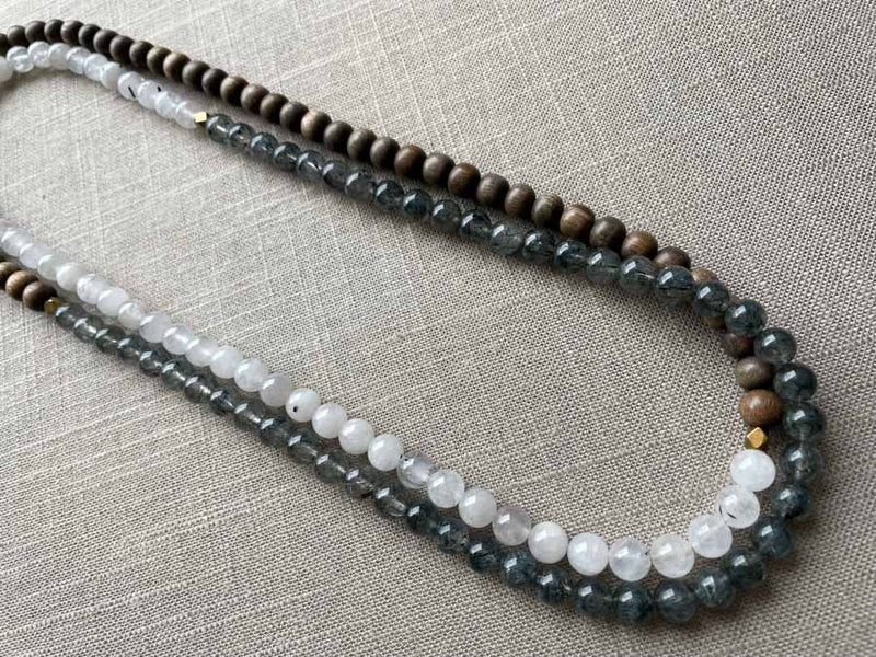 top view of gemstone bead necklace comprising white moonstone, black and white tourmalated quartz and exotic wood