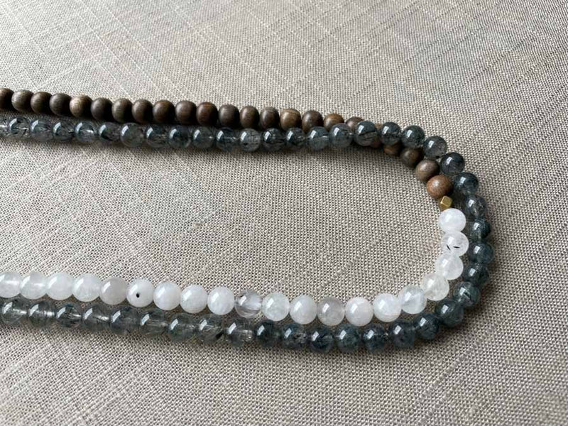 side view of gemstone bead necklace comprising white moonstone, black and white tourmalated quartz and exotic wood