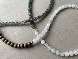 closeup of gemstone bead necklace comprising white moonstone, black and white tourmalated quartz and exotic wood