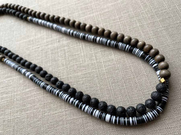 top view of gemstone bead necklace comprising black lava stone, black and white vinyl discs and exotic wood