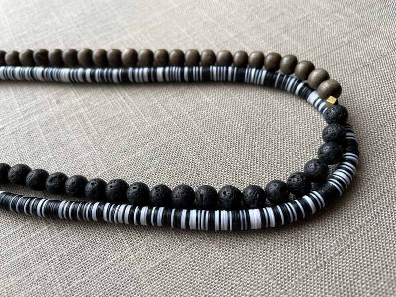 side view of gemstone bead necklace comprising black lava stone, black and white vinyl discs and exotic wood