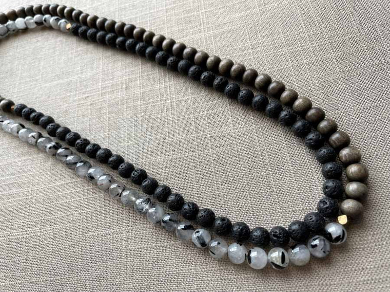 top view of gemstone bead necklace comprising black lava stone, black and white tourmalated quartz and exotic wood