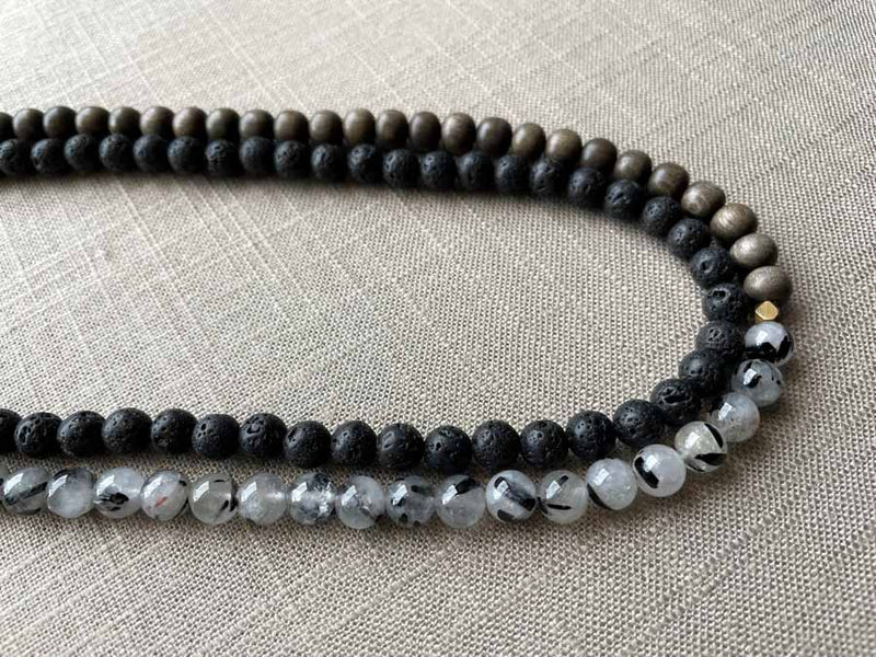 side view of gemstone bead necklace comprising black lava stone, black and white tourmalated quartz and exotic wood