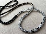 closeup of gemstone bead necklace comprising black lava stone, black and white tourmalated quartz and exotic wood