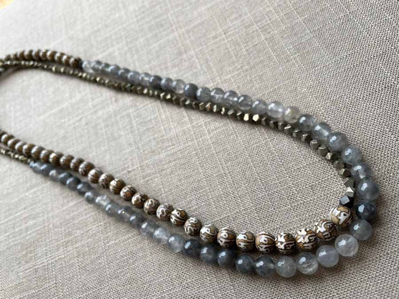 top view of gemstone bead necklace comprising tan prayer beads, black and white tourmalated quartz and dark grey pyrite