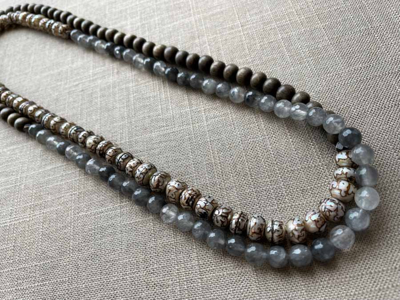 top view of gemstone bead necklace comprising tan prayer beads, black and white tourmalated quartz and exotic wood