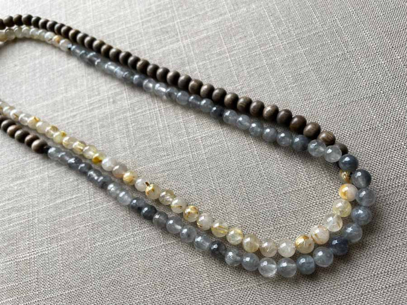 top view of gemstone bead necklace comprising black and white tourmalated quartz, neutral rutilated quartz and exotic wood