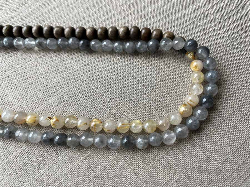 side view of gemstone bead necklace comprising black and white tourmalated quartz, neutral rutilated quartz and exotic wood