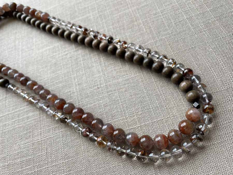 top view of gemstone bead necklace comprising neutral shadow quartz, strawberry quartz and exotic wood