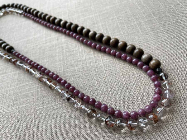 top view of gemstone bead necklace comprising neutral shadow quartz, purple lepidolite and exotic wood