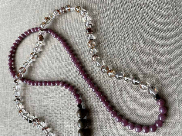 closeup of gemstone bead necklace comprising neutral shadow quartz, purple lepidolite and exotic wood