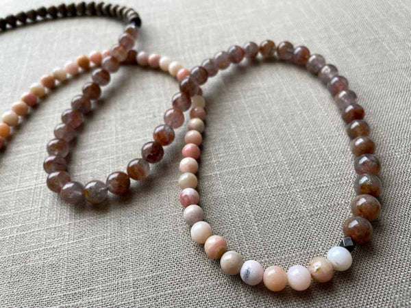 closeup of gemstone bead necklace comprising strawberry quartz, pink opal and exotic wood